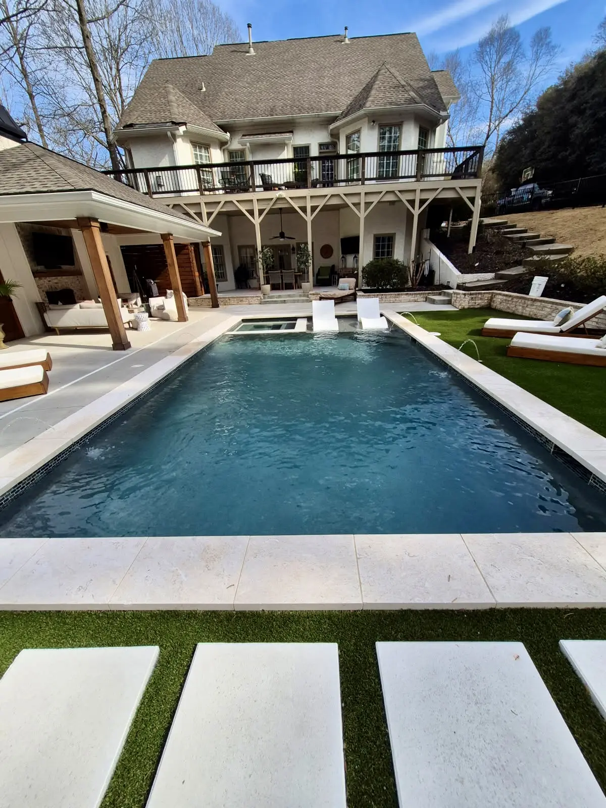 Courtyard pool with water features and white lounge chairs
