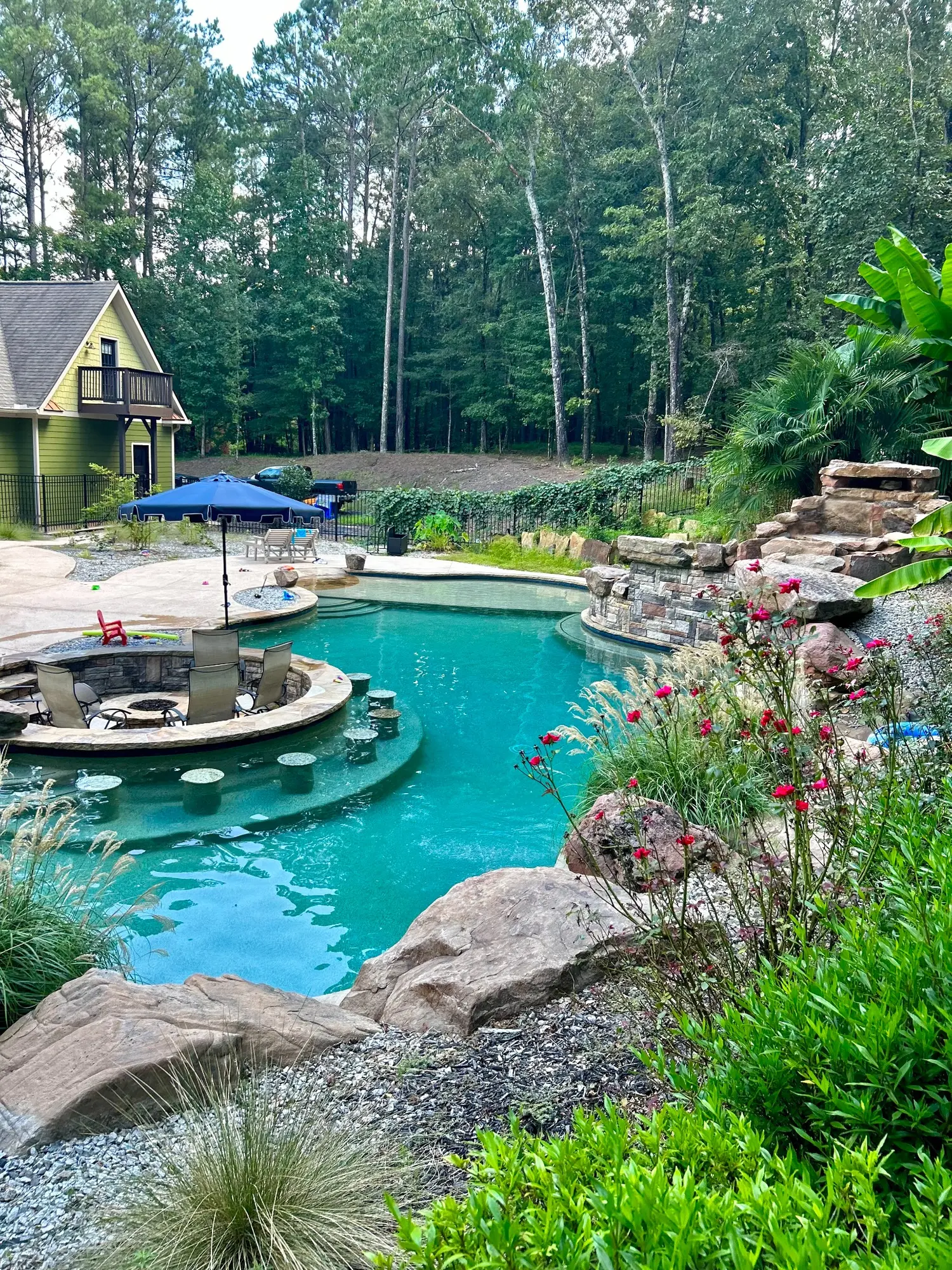 Resort-style pool with lush landscaping, rockwork, and sunken seating