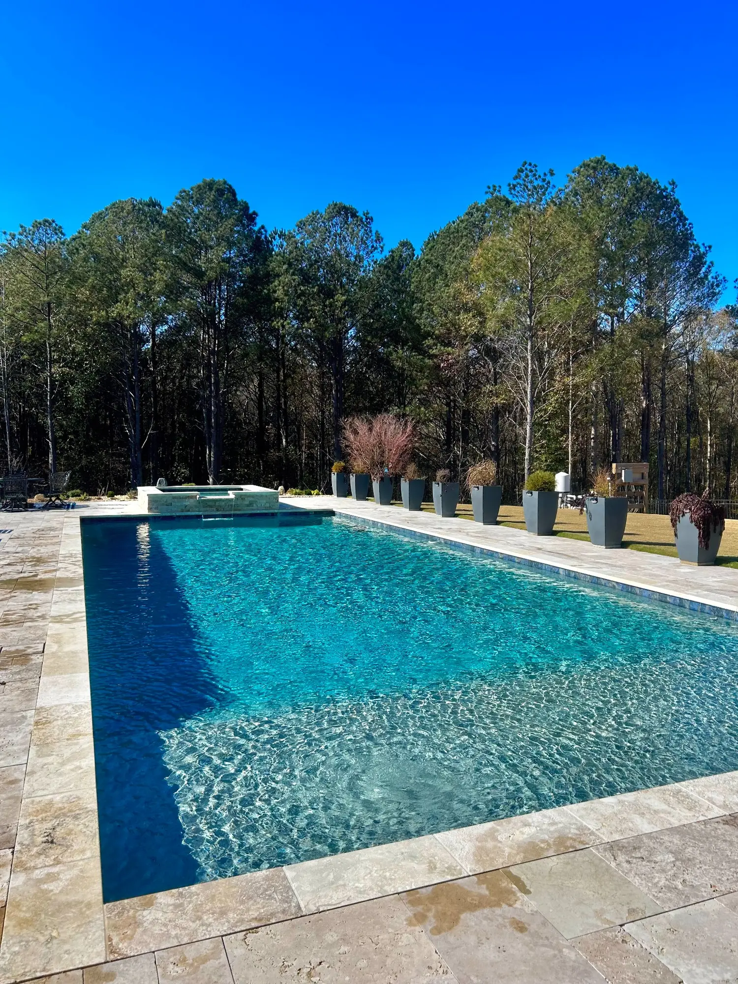 Long blue pool surrounded by stone and a line of planters