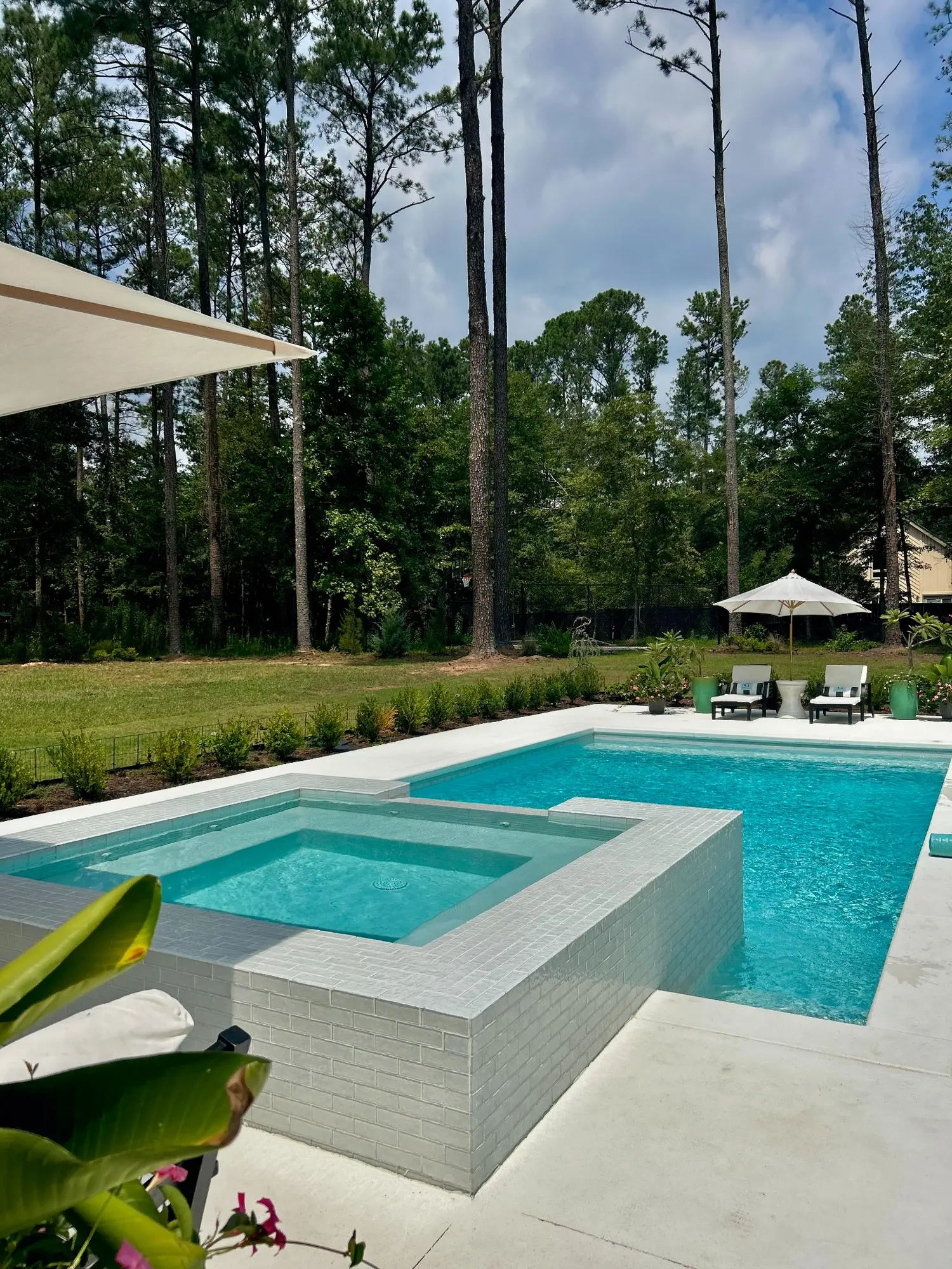 White raised spa overlooking a clear rectangular pool